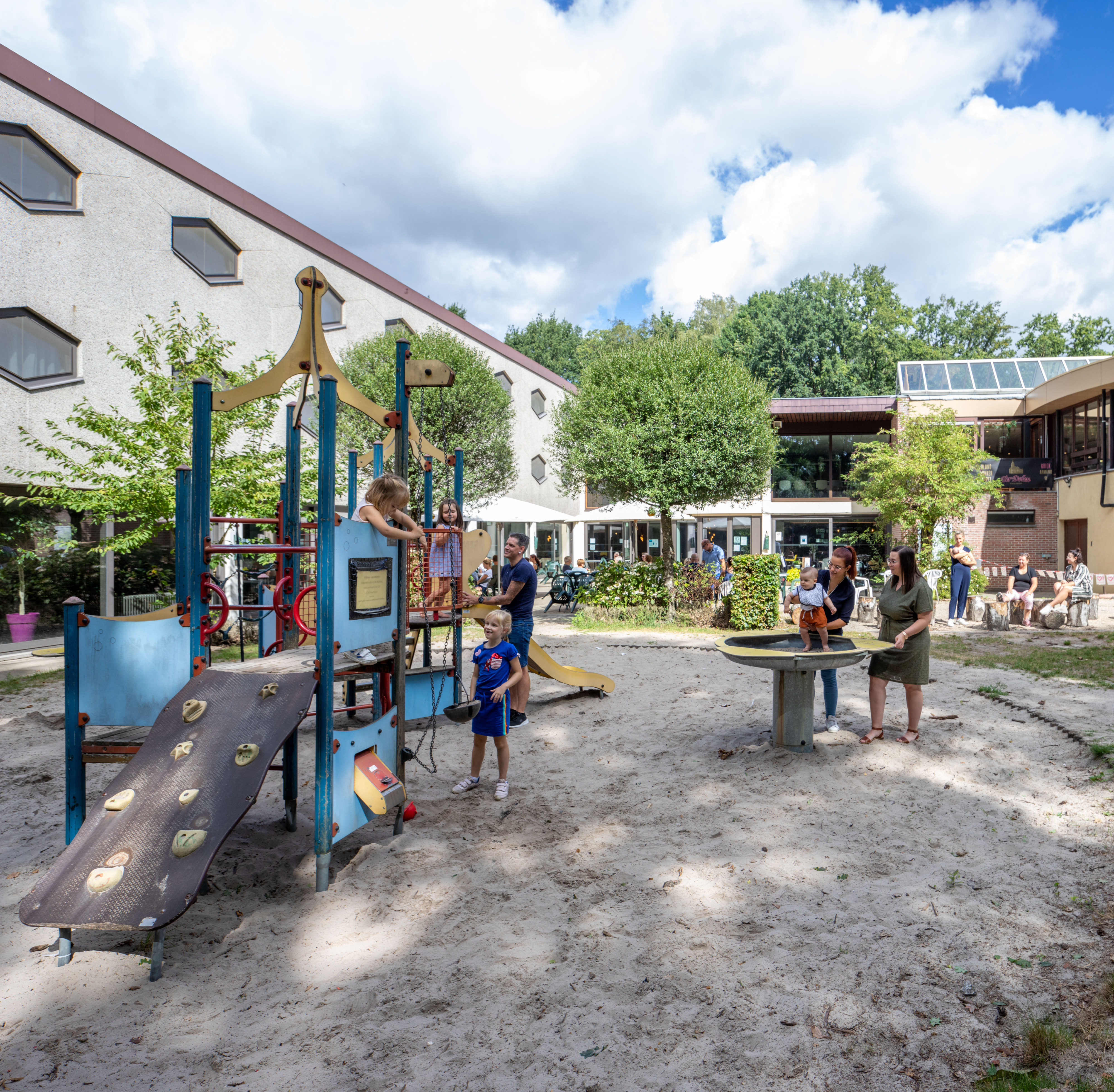 spelende kinderen op speelplein in zandbak met gebouw op de achtergrond