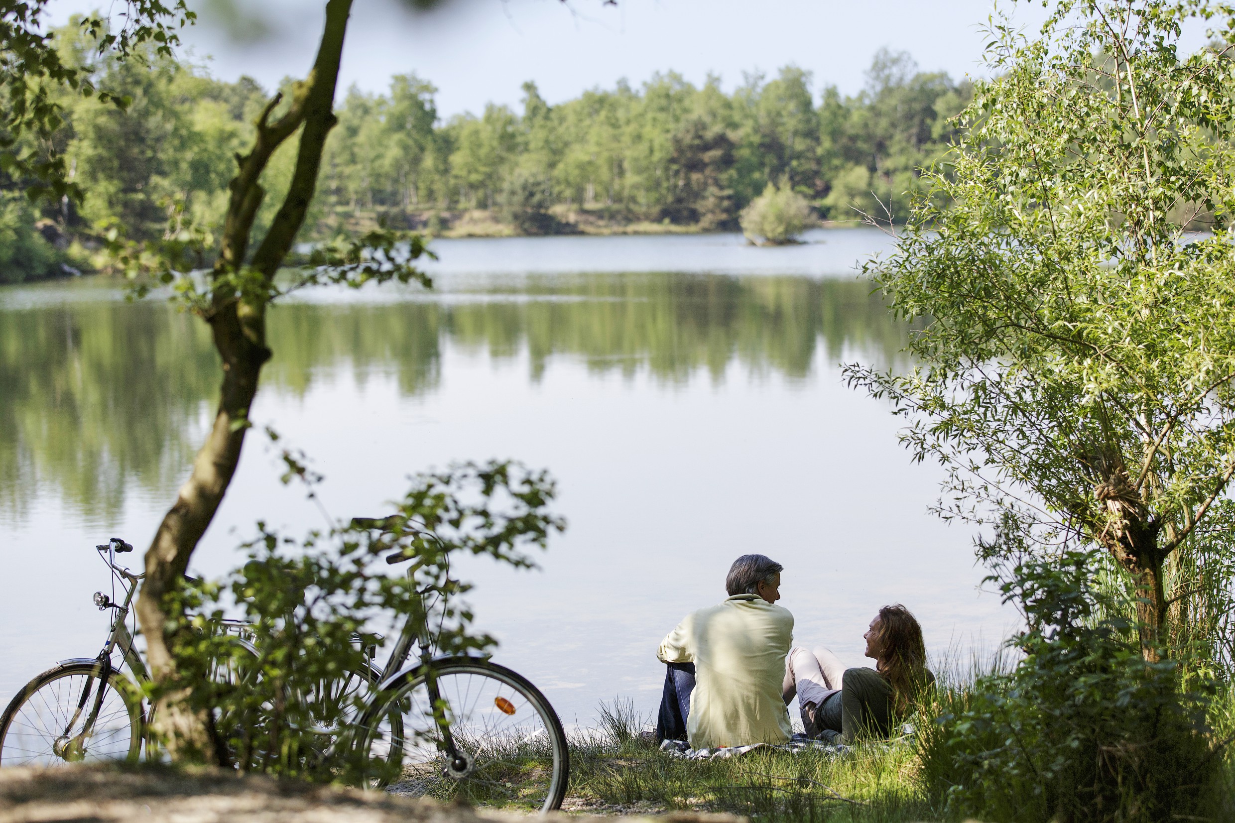 twee mensen met fiets die aan een meer zitten