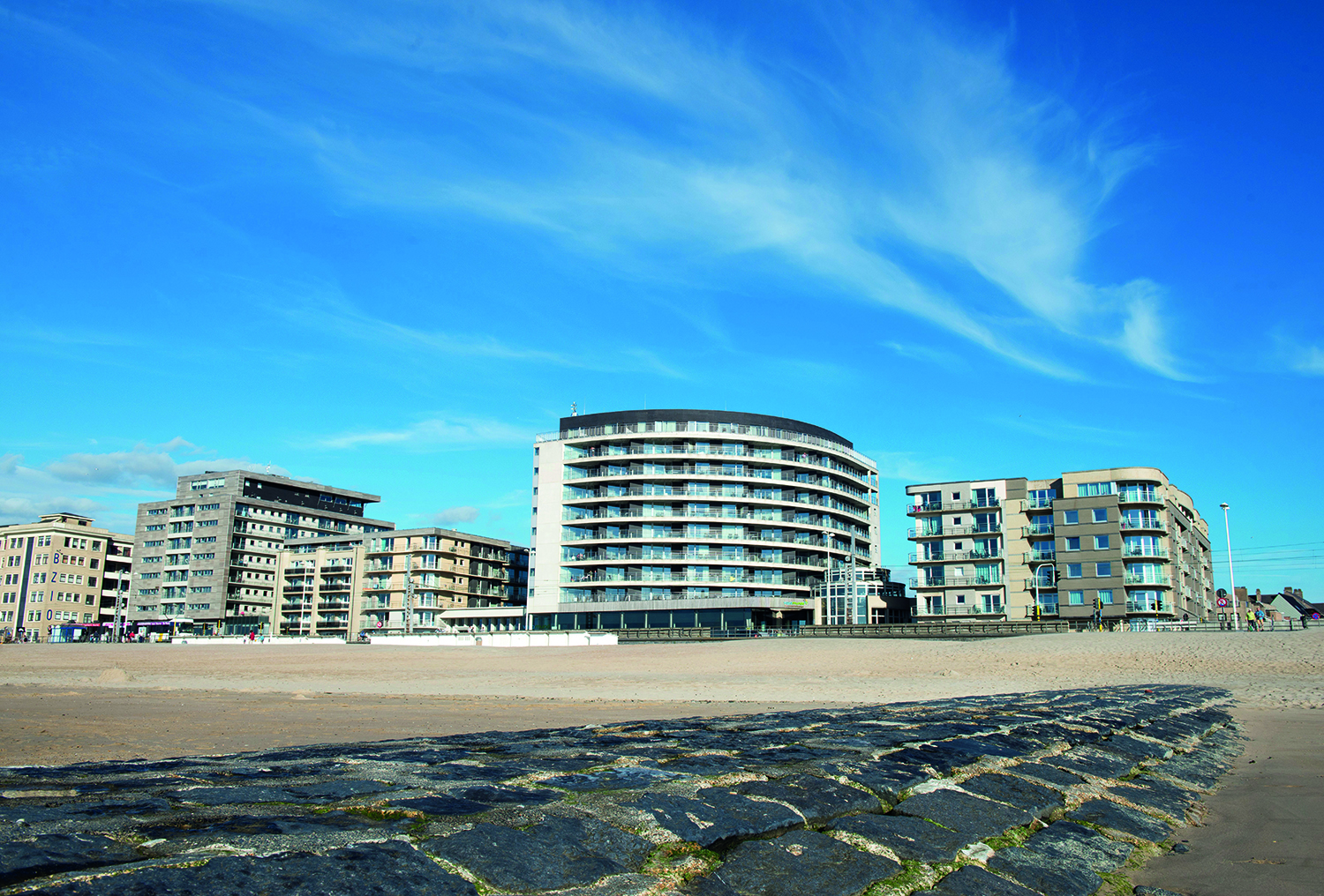 foto met appartementsblokken en hotels aan het strand en golfbreker