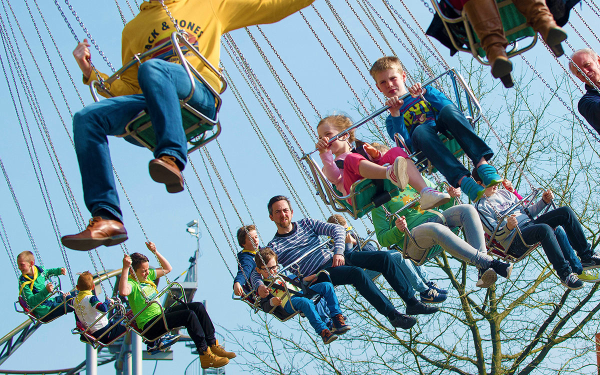 mensen op attractie van vliegende carrousel (stoeltjes aan kettingen die ronddraaien)