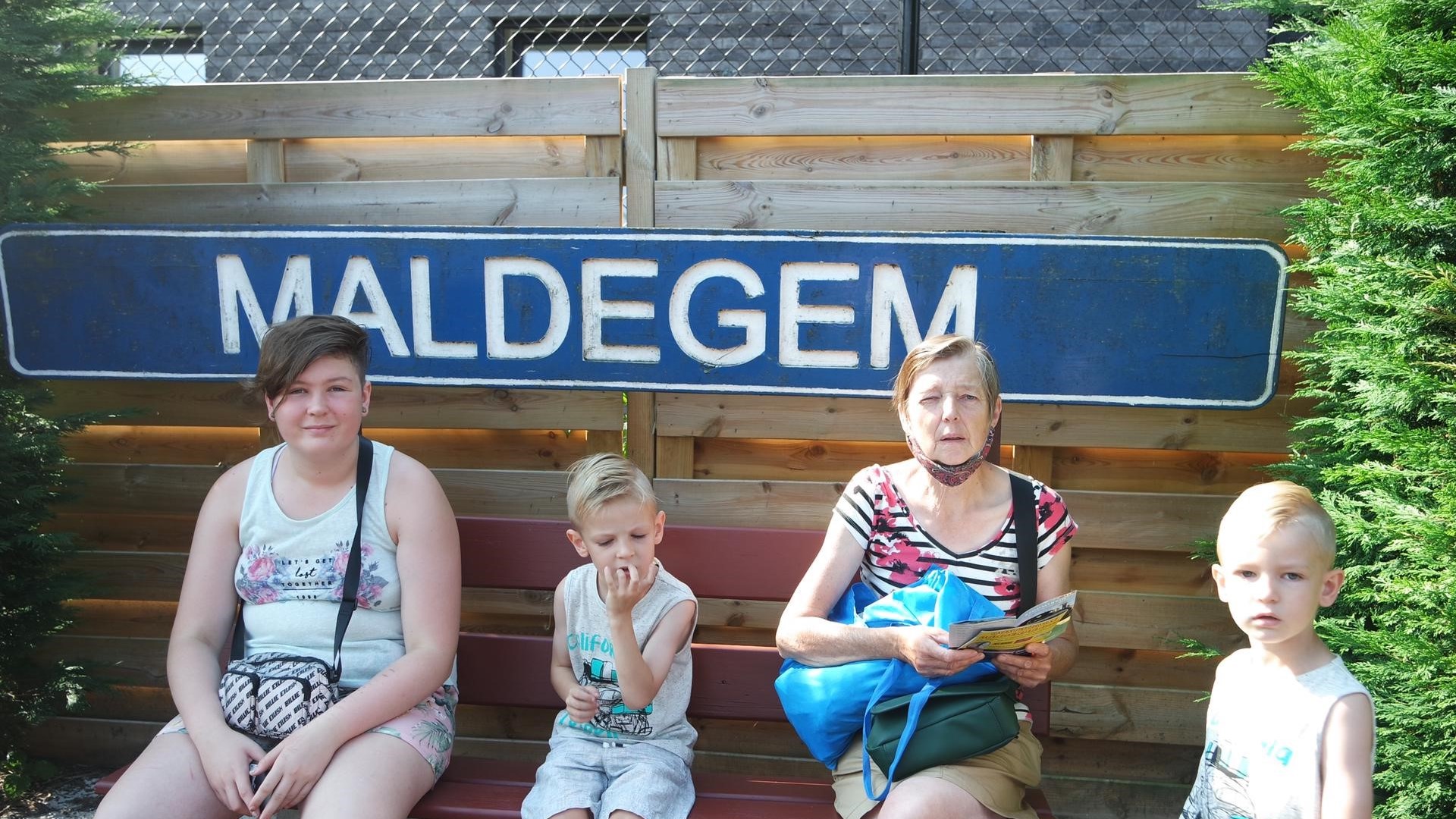 oma met meisje en twee jongens voor woord Maldegem op bankje