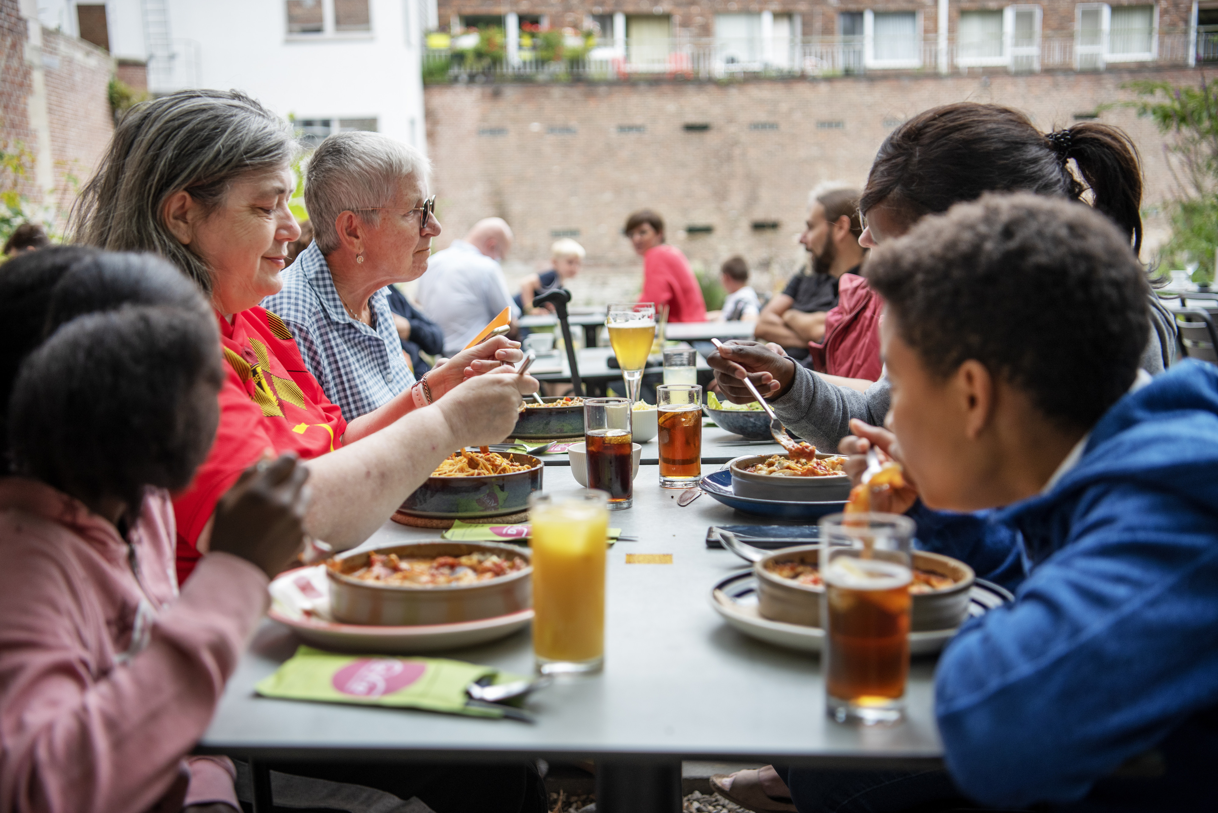 kinderen en volwassenen zitten samen buiten aan tafel te eten