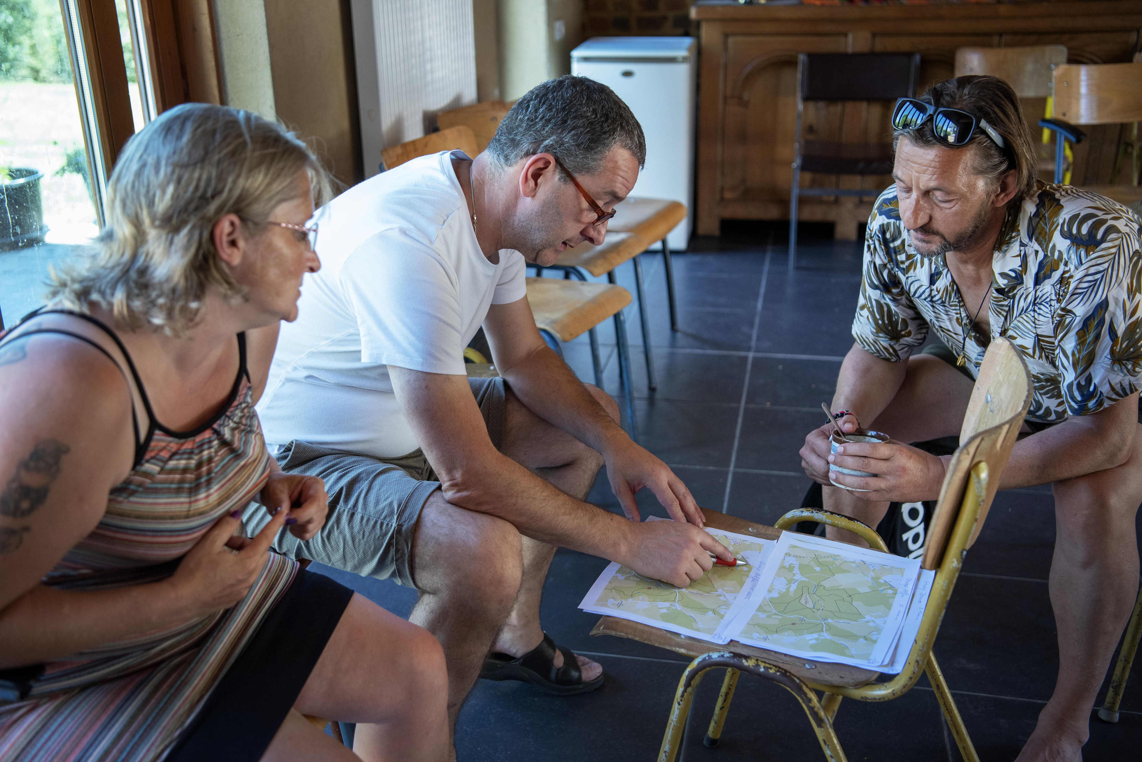 drie mensen zitten neer en buigen zich over plan