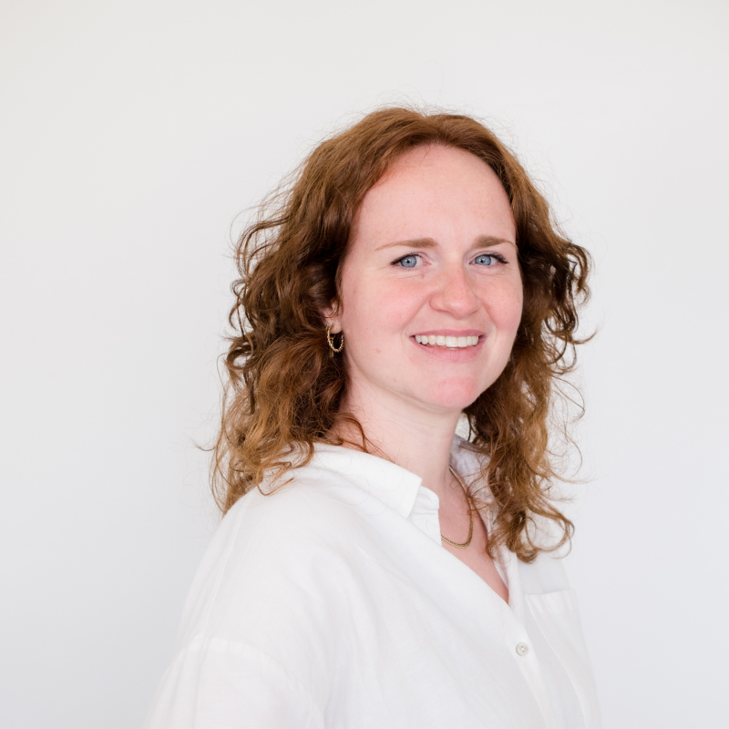 dame met ros krullen halflang haar en witte bloes