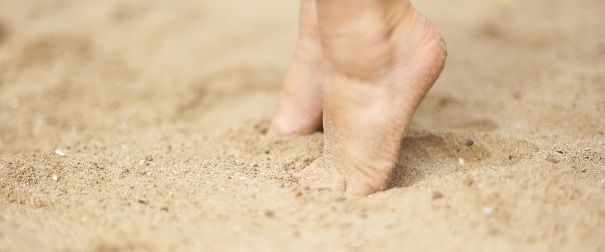 twee kindervoeten op de toppen van de tenen in het zand